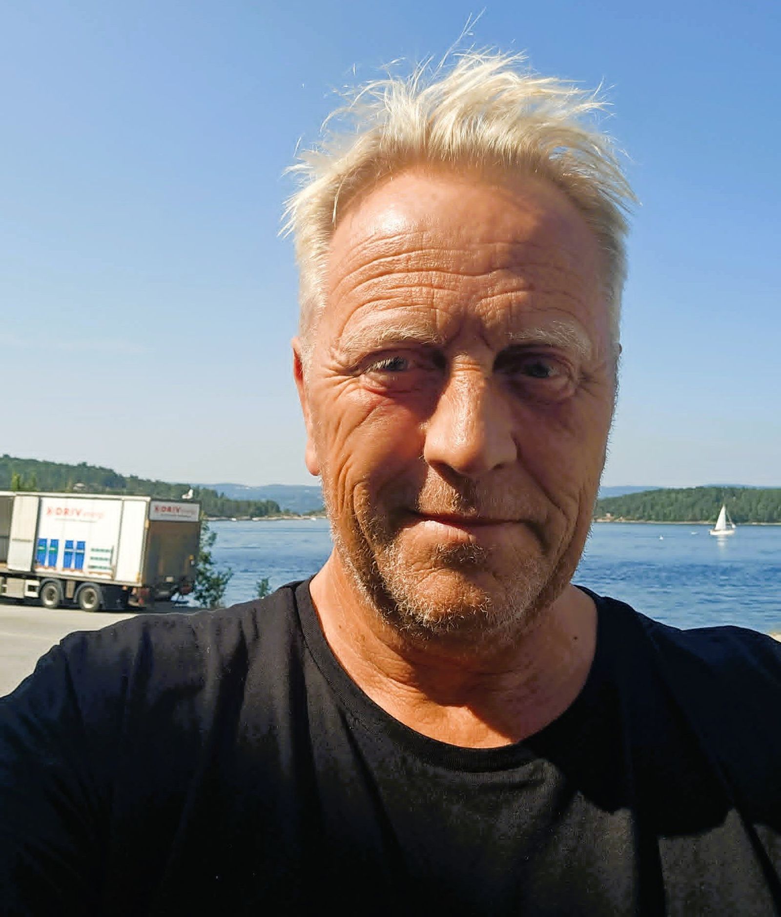 Re-Duce-grunnlegger Arne Karlsen tar en selfie ved fjorden, med en DRIV Energi-lastebil i bakgrunnen.