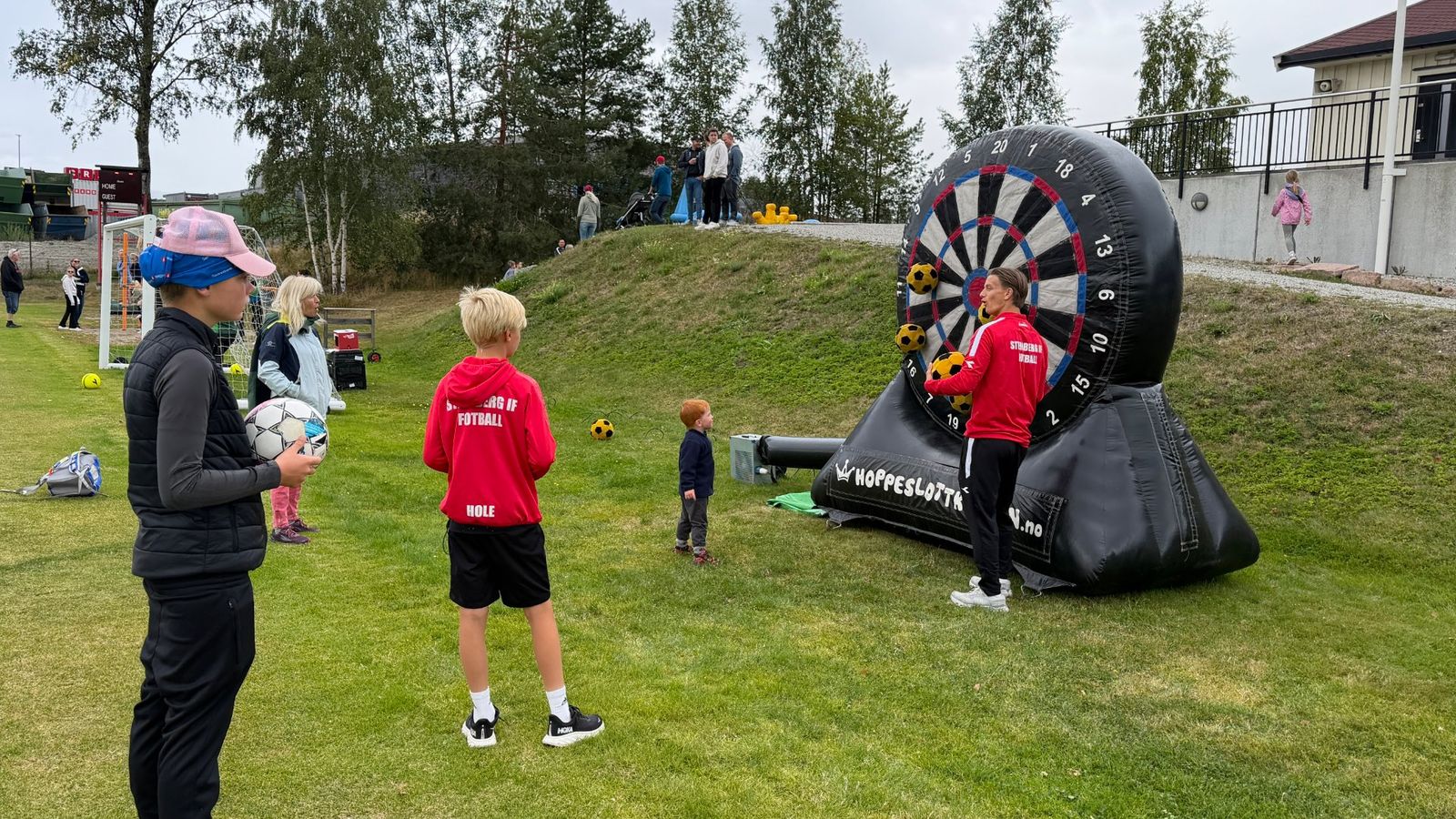 Barn og unge kastet fotball på oppblåsbar dartskive under jubileumsfeiringen til Steinberg IF, mens flere generasjoner samlet seg rundt aktivitetene.