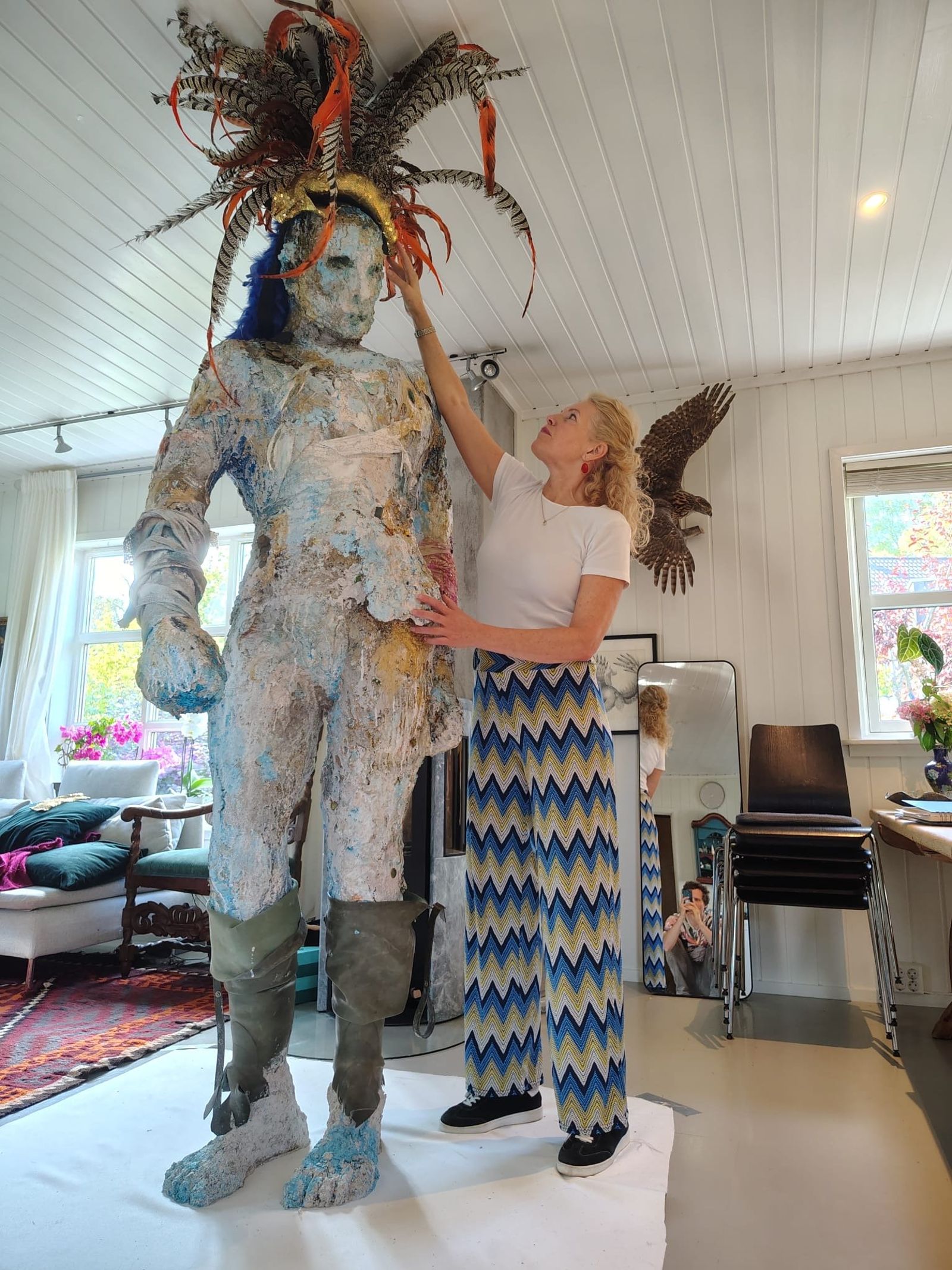 Henriette Finne justerer fjærpryden på sin over to meter høye skulptur, bygget opp av rest-plast og gamle gummistøvler.