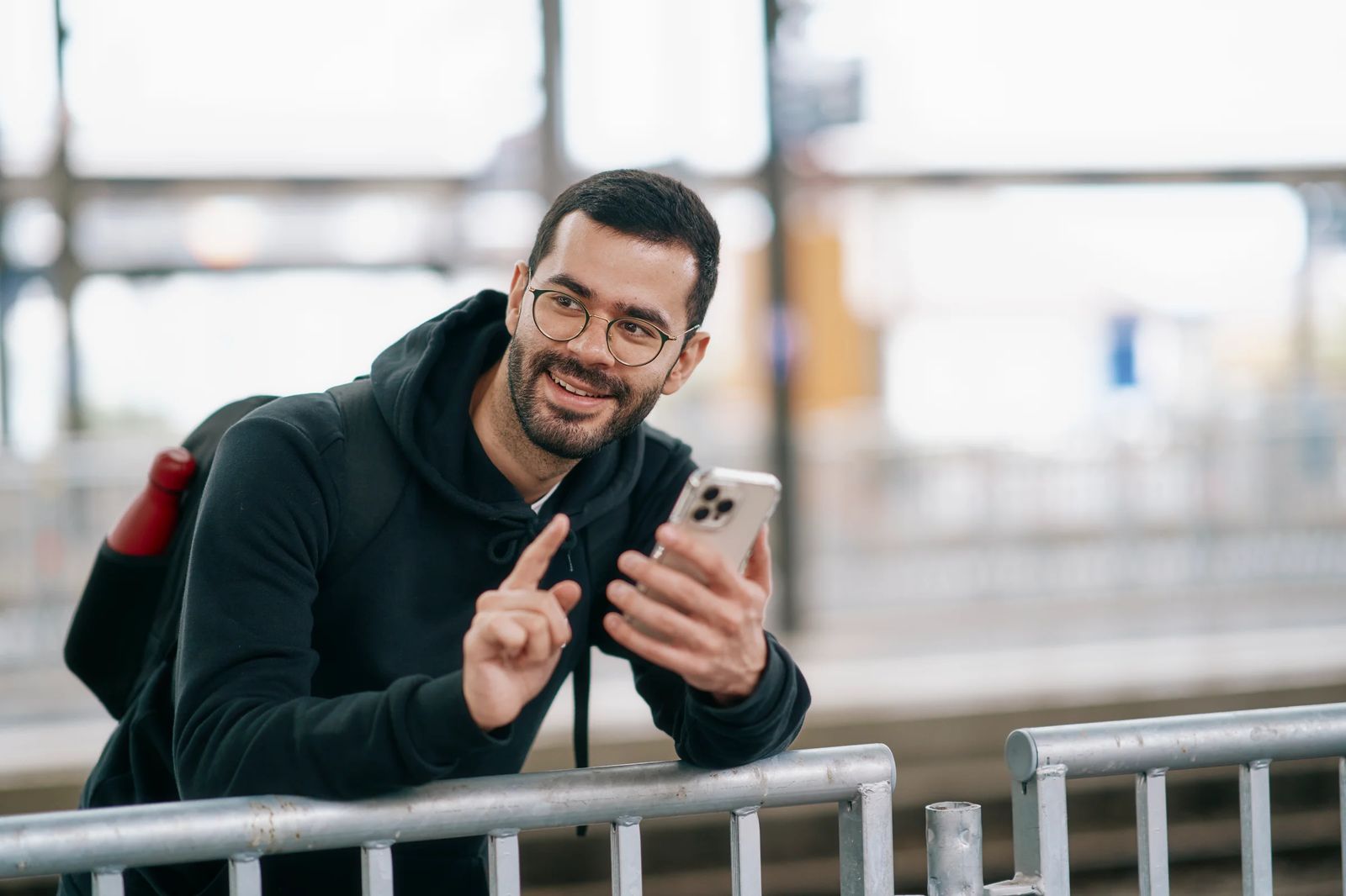 En mann sjekker FAIRTIQ-appen på mobilen mens han venter på bussen.